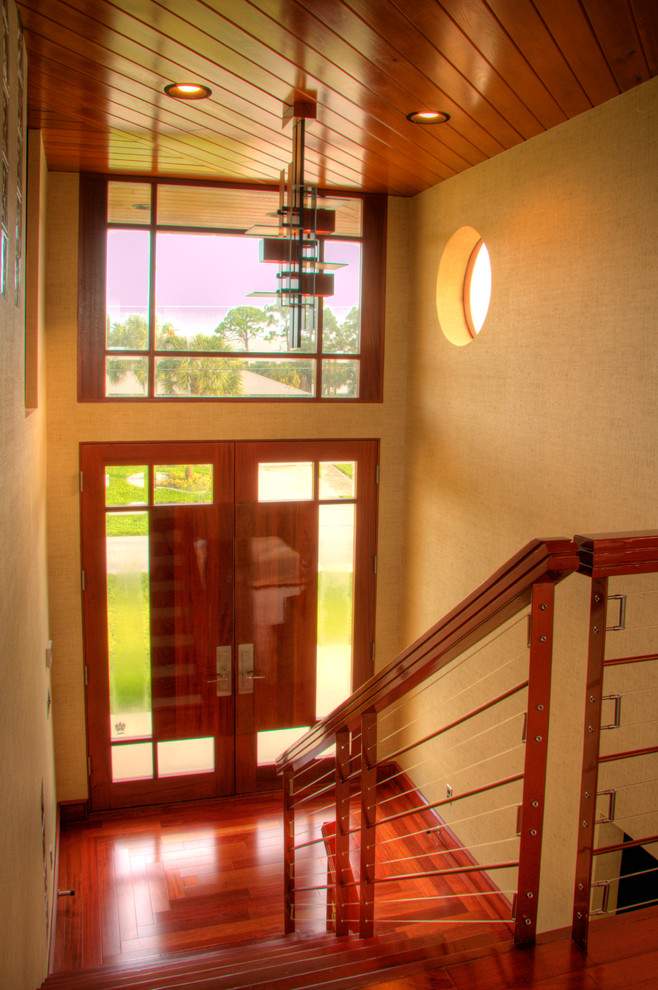 Idee per un ingresso minimal di medie dimensioni con pareti beige, pavimento in legno massello medio, una porta a due ante, una porta in legno chiaro e pavimento marrone