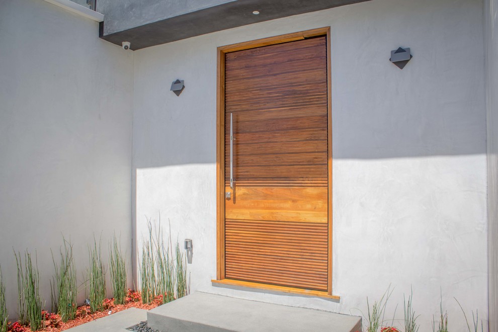 Foto de puerta principal actual de tamaño medio con paredes blancas, puerta simple, puerta de madera en tonos medios, suelo de cemento y suelo gris