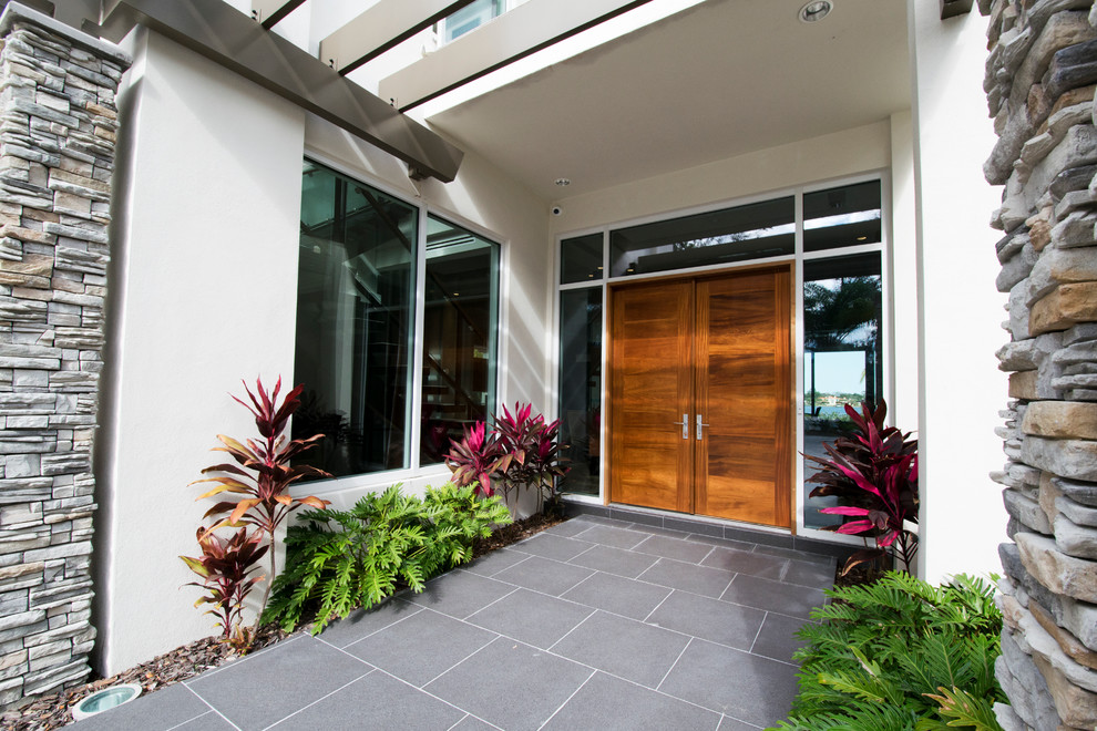 This is an example of an expansive contemporary front door in Orlando with white walls, porcelain flooring, a double front door and a medium wood front door.