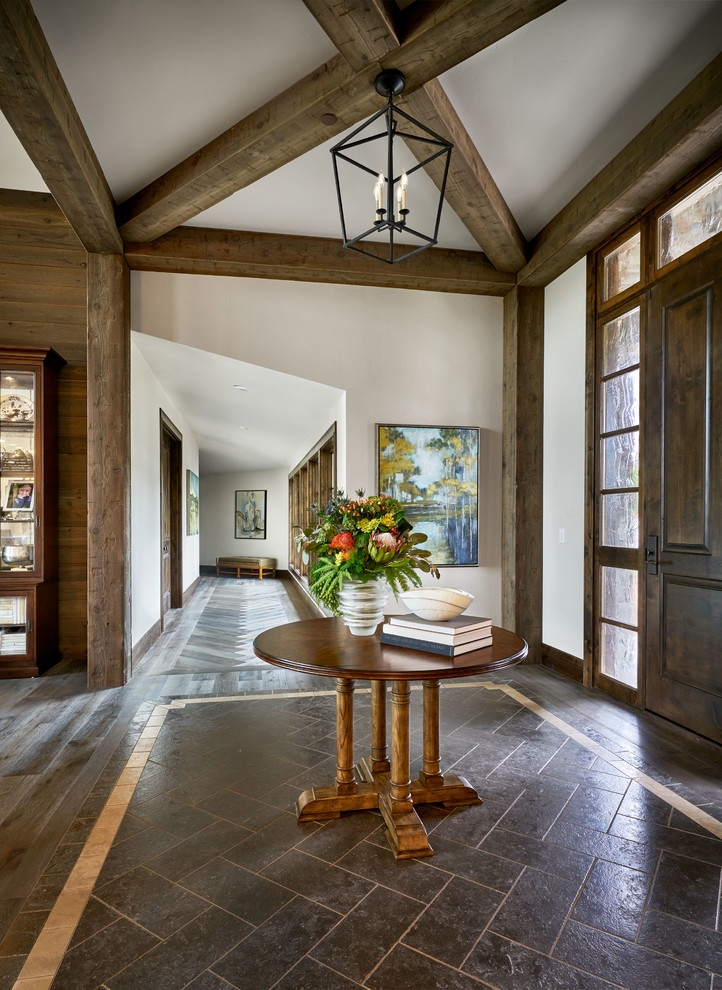 Photo of a large farmhouse foyer in Portland with grey walls, limestone flooring, a single front door, a dark wood front door and brown floors.