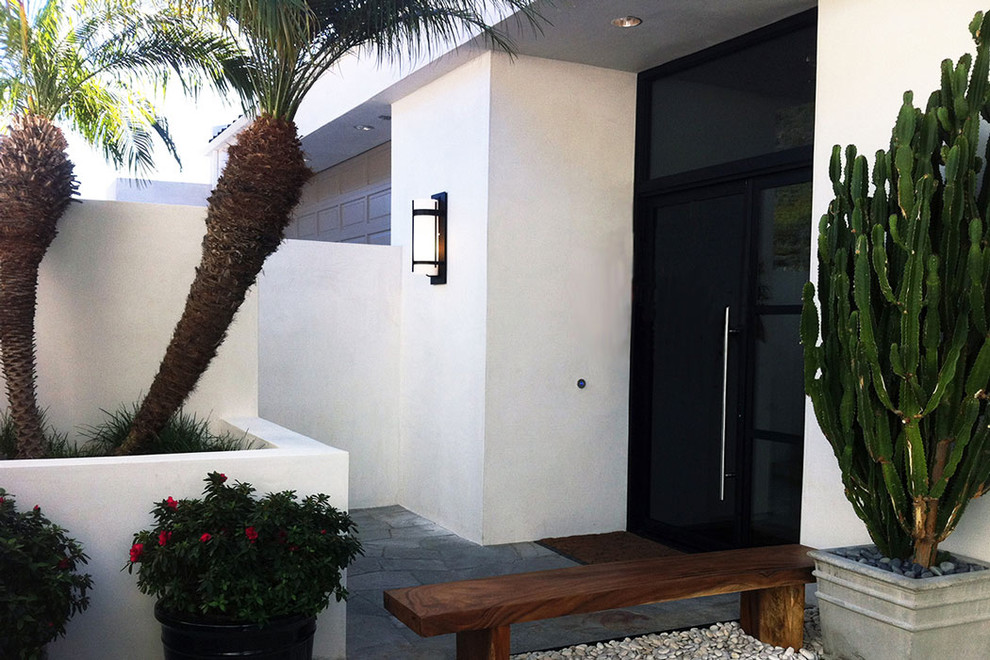Ispirazione per una porta d'ingresso tropicale di medie dimensioni con pareti bianche, pavimento in ardesia, una porta in metallo e una porta a pivot