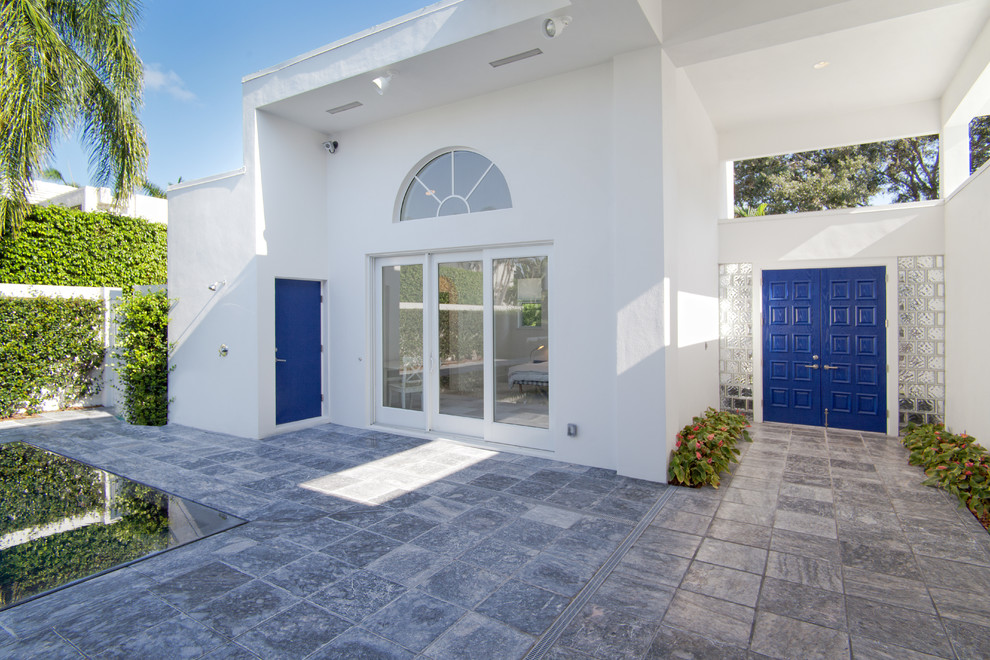 Foto de puerta principal minimalista grande con paredes blancas, suelo de pizarra, puerta doble y puerta azul