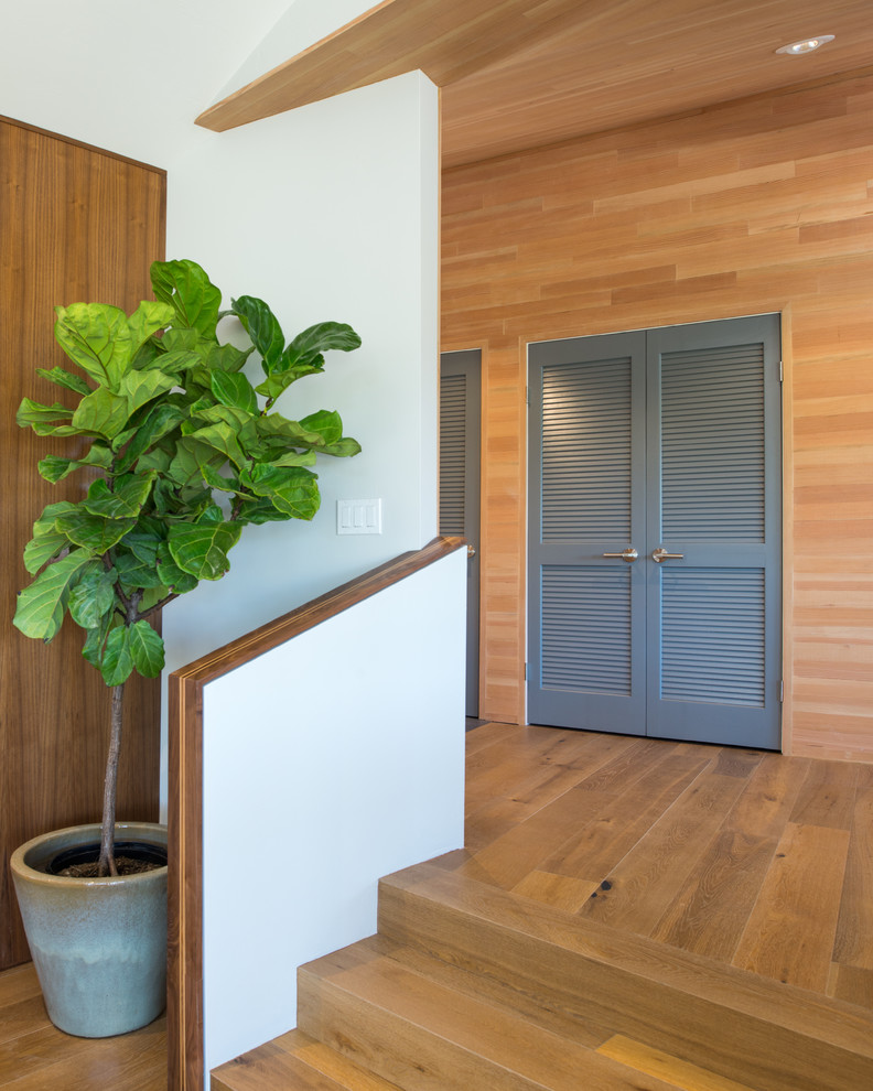 Aménagement d'une grande porte d'entrée contemporaine avec un sol en bois brun, une porte simple et une porte en bois brun.