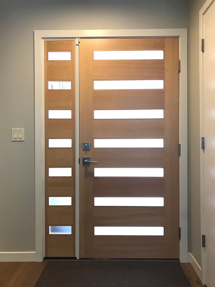 Immagine di una porta d'ingresso minimalista di medie dimensioni con pareti grigie, pavimento in legno massello medio, una porta singola e una porta in legno chiaro