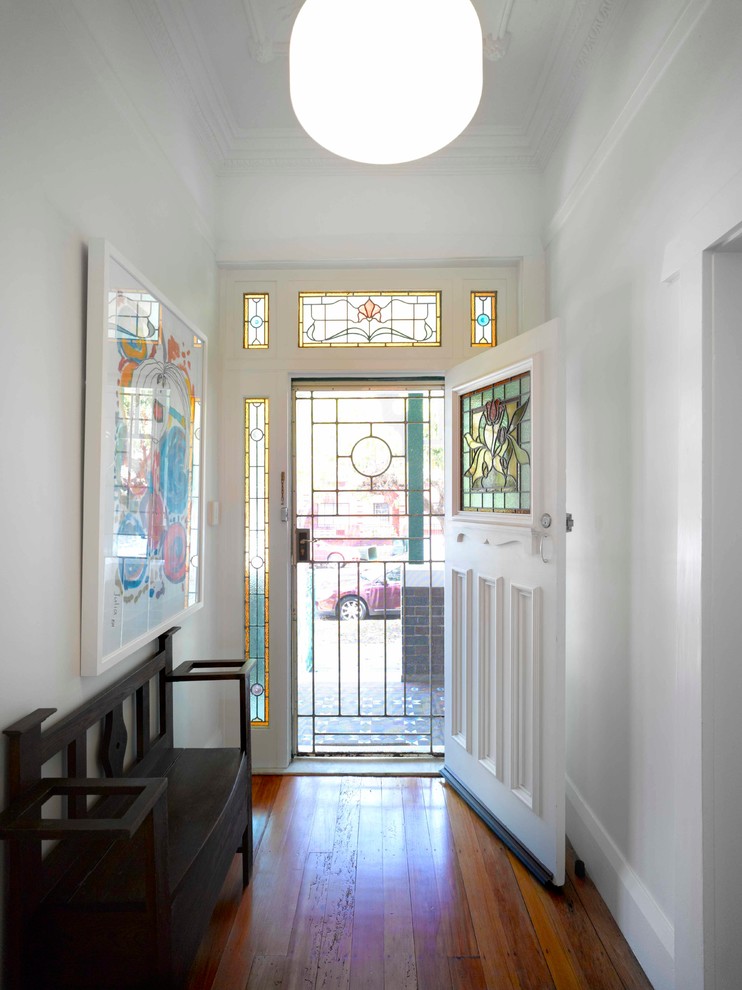 Esempio di una porta d'ingresso design di medie dimensioni con pareti bianche, pavimento in legno massello medio, una porta singola, una porta bianca e pavimento marrone