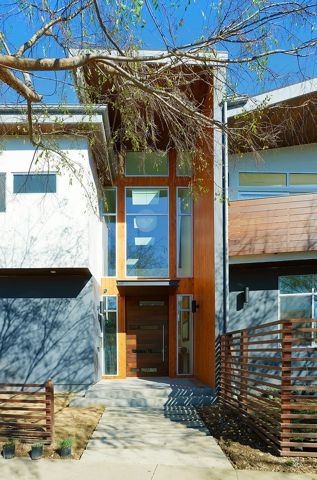 Exempel på en mellanstor modern ingång och ytterdörr, med bruna väggar, betonggolv, en pivotdörr och mörk trädörr