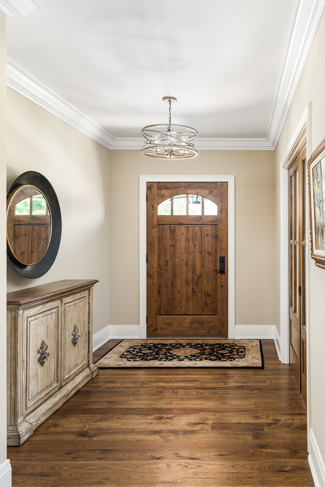 Idée de décoration pour un grand hall d'entrée tradition avec un mur beige, parquet foncé, une porte simple, une porte en bois brun et un sol marron.