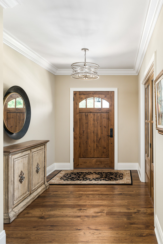 Modelo de distribuidor tradicional grande con paredes beige, suelo de madera oscura, puerta simple, puerta de madera en tonos medios y suelo marrón