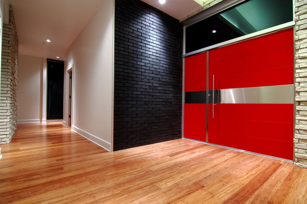 Idée de décoration pour une grande porte d'entrée design avec parquet en bambou, un mur blanc, une porte simple, une porte rouge et un sol marron.
