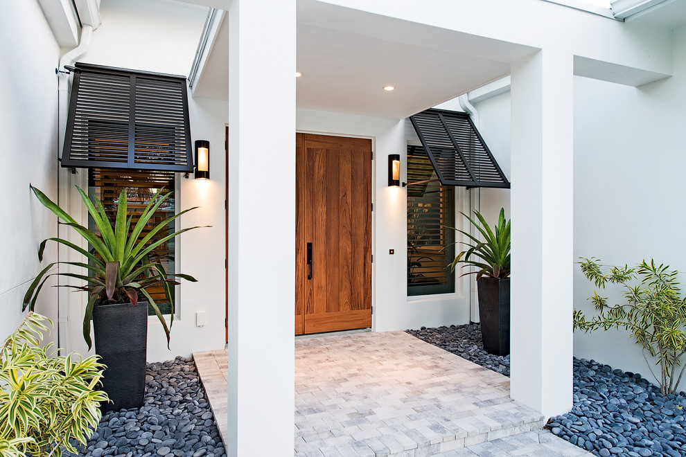 Aménagement d'une grande porte d'entrée exotique avec un mur blanc, un sol en ardoise, une porte en bois brun, un sol blanc et une porte double.