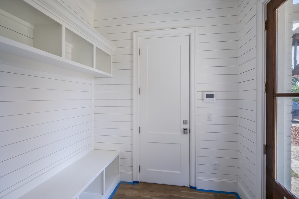 Modelo de vestíbulo posterior clásico pequeño con paredes blancas, suelo de madera en tonos medios, puerta simple, puerta blanca y suelo marrón