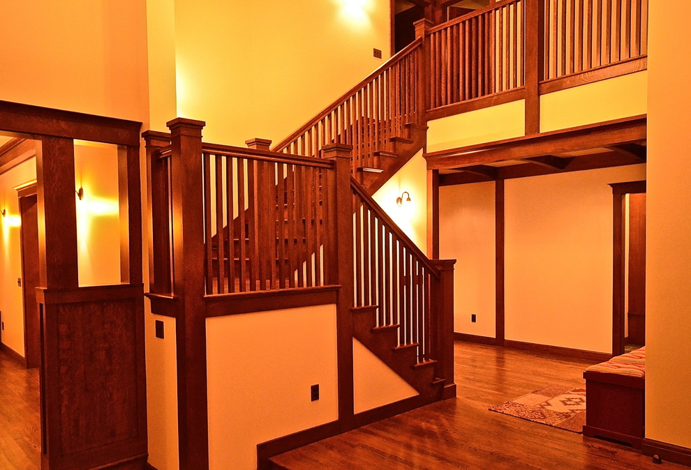 Idées déco pour un grand hall d'entrée craftsman avec un mur beige et un sol en bois brun.