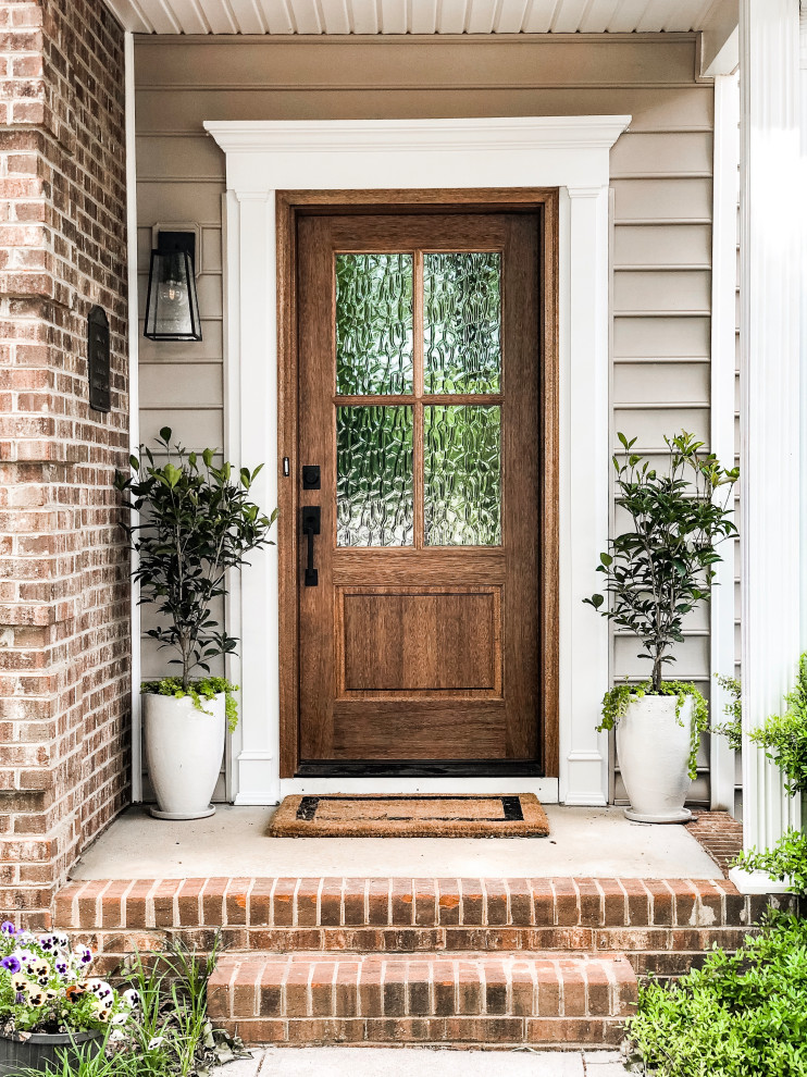 Réalisation d'une porte d'entrée tradition de taille moyenne avec un mur beige, sol en béton ciré, une porte simple, une porte en bois brun et un sol gris.