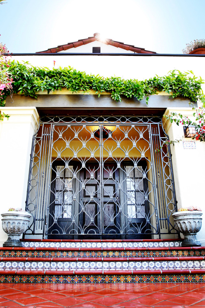 Modelo de puerta principal mediterránea grande con paredes beige, suelo de baldosas de cerámica, puerta doble y puerta metalizada