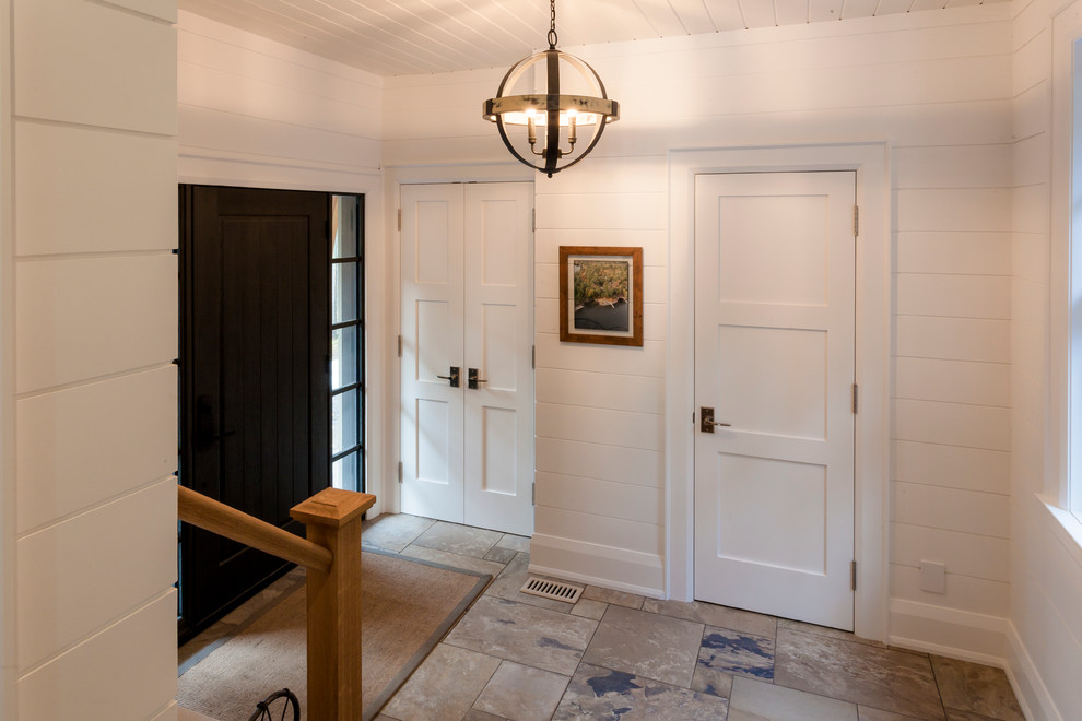 Imagen de puerta principal tradicional grande con paredes blancas, suelo de pizarra, puerta pivotante y puerta negra