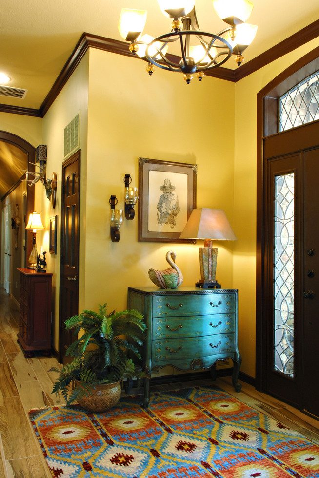 Immagine di un grande ingresso american style con pareti gialle, parquet chiaro, una porta singola e una porta in legno scuro