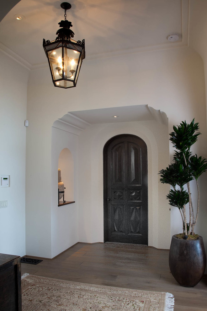 Entryway - mid-sized mediterranean medium tone wood floor entryway idea in San Diego with white walls and a dark wood front door