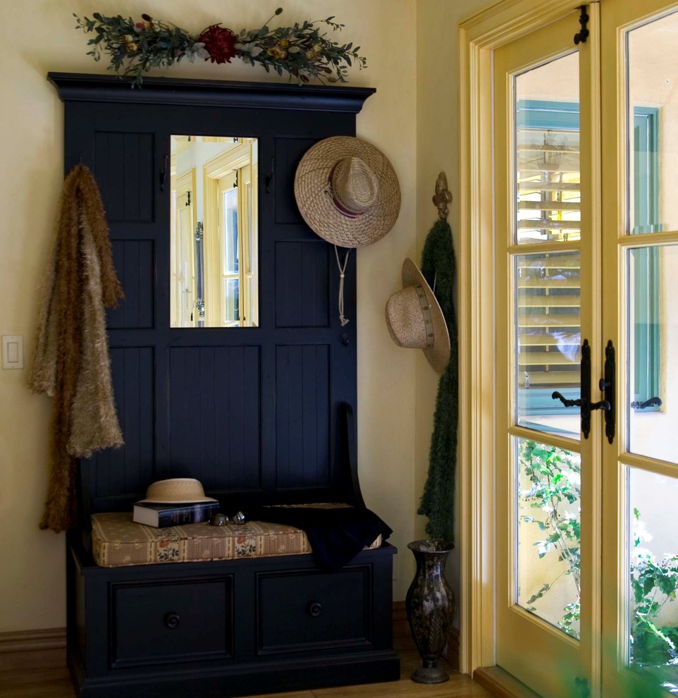 Inspiration for a mid-sized timeless medium tone wood floor and brown floor entryway remodel in Orange County with yellow walls and a yellow front door
