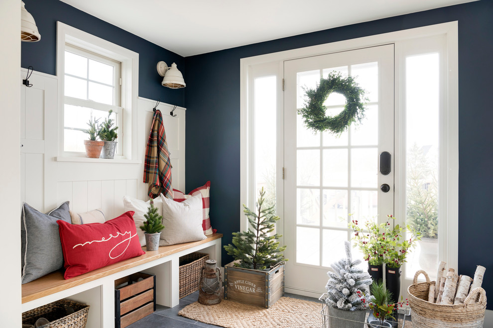 Idée de décoration pour une entrée champêtre de taille moyenne avec un mur bleu, une porte simple, un sol gris, un vestiaire et une porte en verre.