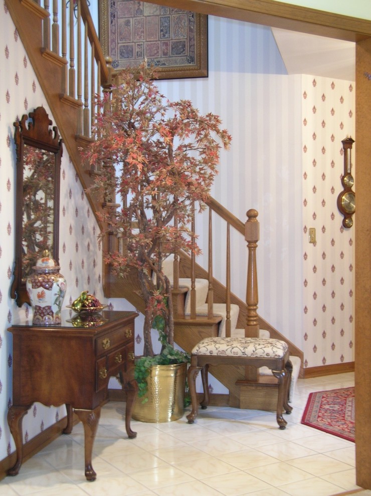 Aménagement d'une petite porte d'entrée classique avec un mur blanc, un sol en carrelage de céramique et une porte en bois brun.