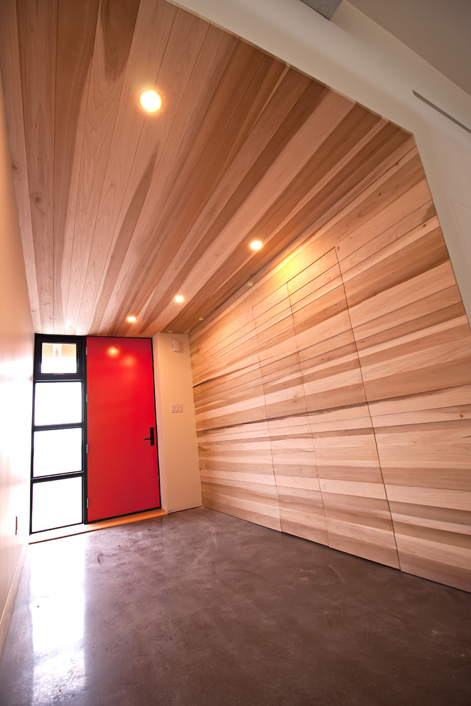 Aménagement d'un hall d'entrée moderne de taille moyenne avec un mur blanc, sol en béton ciré, une porte pivot, une porte rouge et un sol gris.