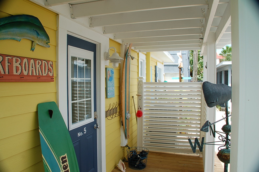 タンパにある中くらいなビーチスタイルのおしゃれなマッドルーム (黄色い壁、無垢フローリング、青いドア) の写真