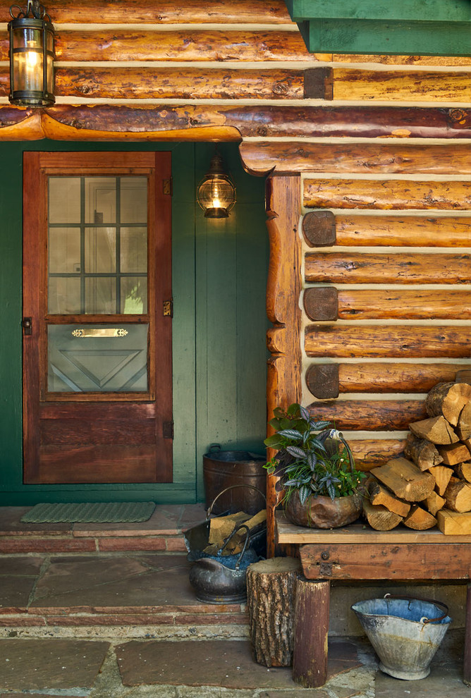 Réalisation d'une grande porte d'entrée chalet avec une porte simple, un mur vert, une porte en bois foncé et un sol marron.