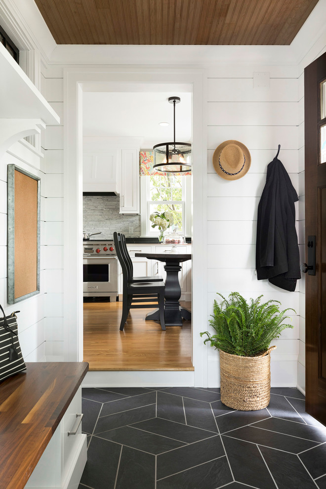 Ejemplo de hall de estilo de casa de campo con paredes blancas, puerta de madera oscura, suelo negro y puerta simple