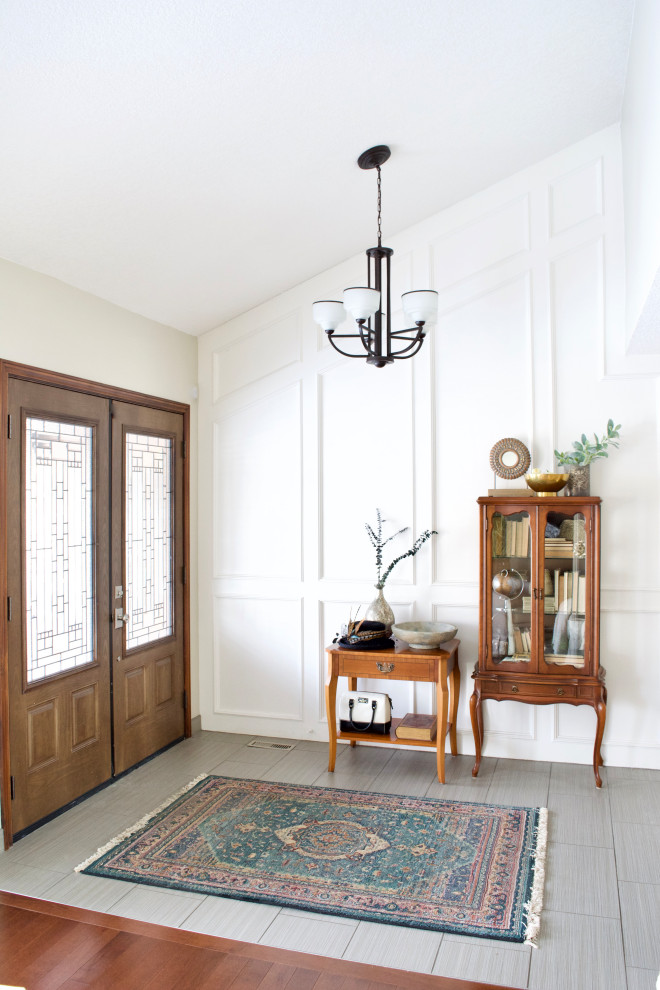 Transitional gray floor, vaulted ceiling and wall paneling entryway photo in Calgary with white walls and a white front door