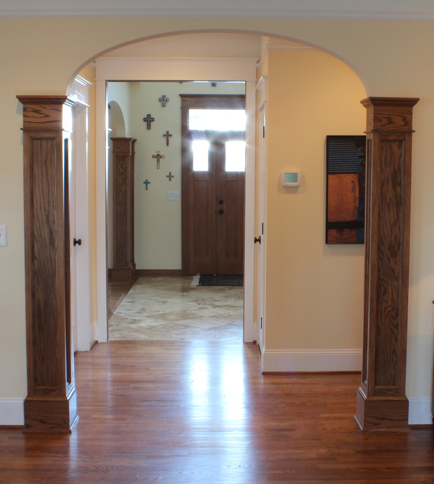 Idées déco pour une entrée classique avec un couloir, un mur jaune, une porte simple et une porte en bois brun.