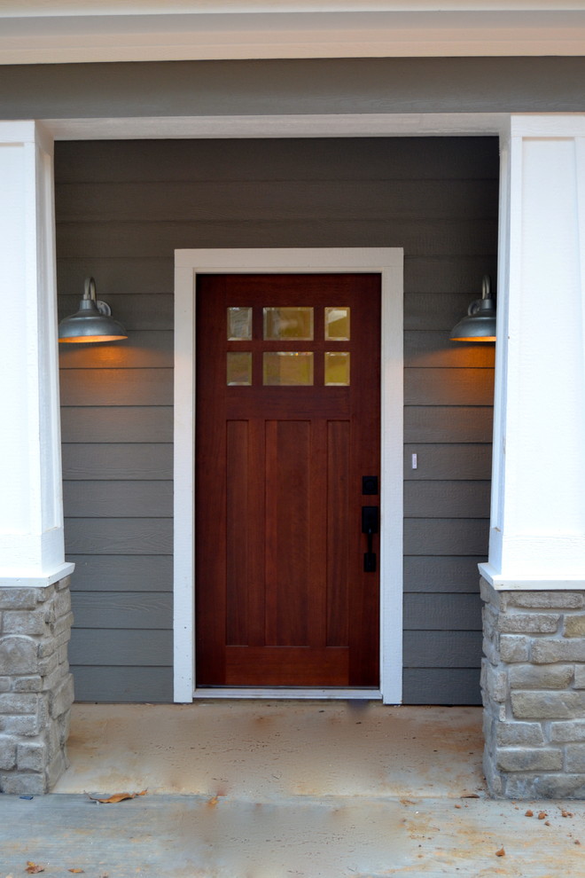 This is an example of a small traditional front door in Dallas with grey walls, concrete flooring, a single front door and a dark wood front door.