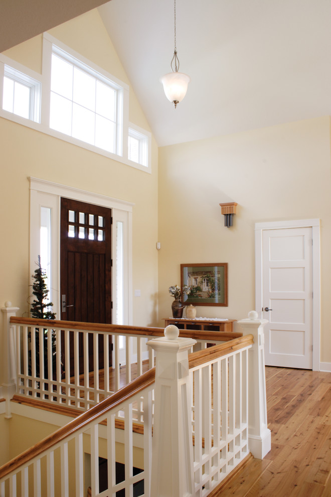 Diseño de puerta principal de estilo americano pequeña con paredes beige, suelo de madera clara y puerta de madera oscura