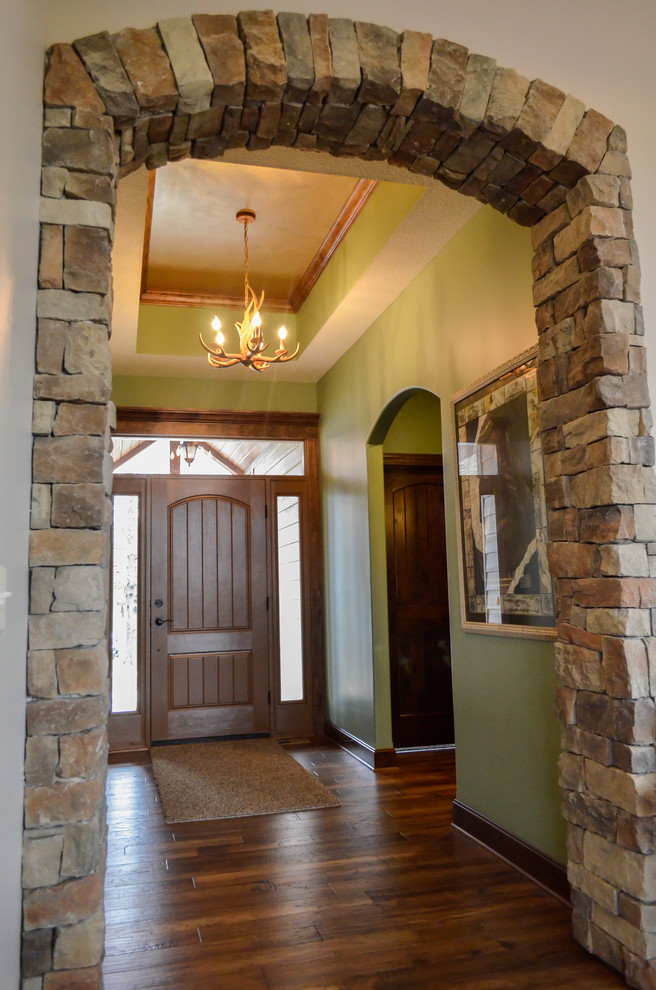 Imagen de distribuidor rústico de tamaño medio con paredes verdes, suelo de madera oscura, puerta simple y puerta de madera en tonos medios