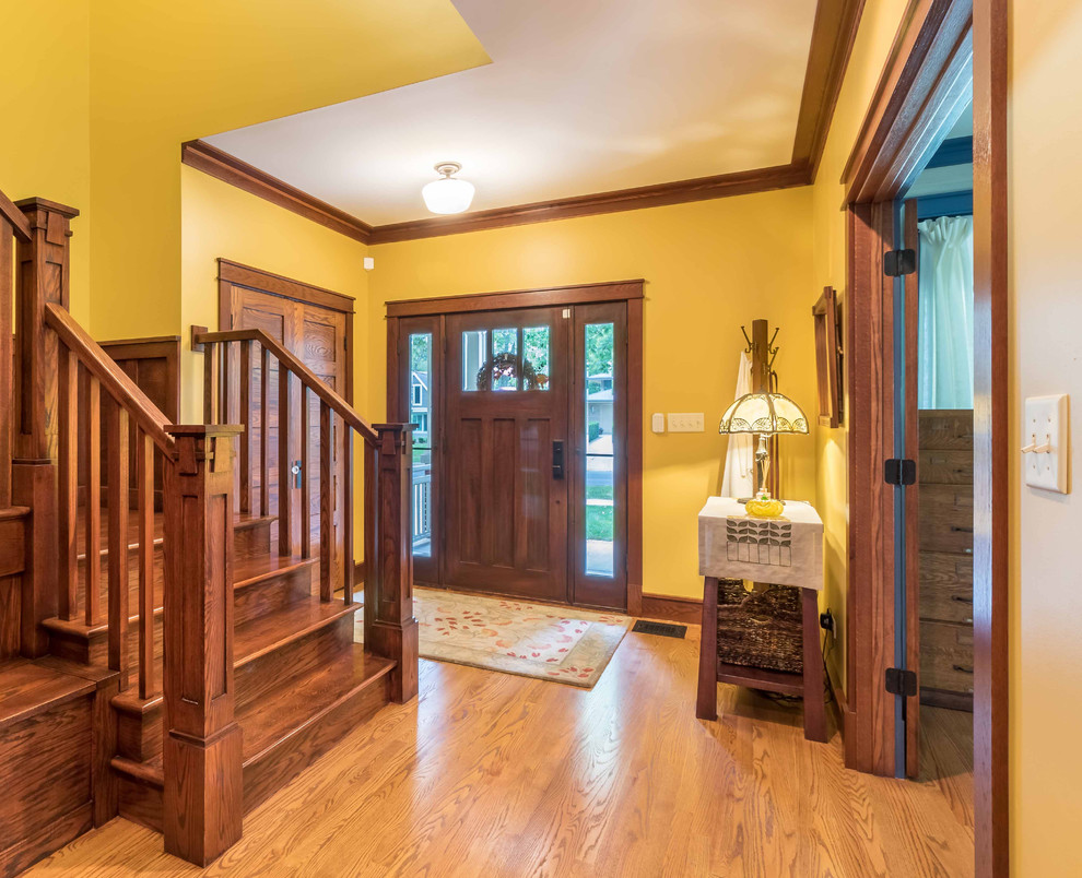 Mittelgroßes Rustikales Foyer mit gelber Wandfarbe, hellem Holzboden, Einzeltür, hellbrauner Holzhaustür, braunem Boden, Treppe, Tapetendecke und Tapetenwänden in Chicago