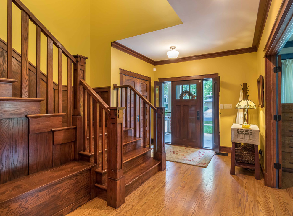 Mittelgroßes Rustikales Foyer mit gelber Wandfarbe, hellem Holzboden, Einzeltür, hellbrauner Holzhaustür, braunem Boden, Treppe, Tapetendecke und Tapetenwänden in Chicago