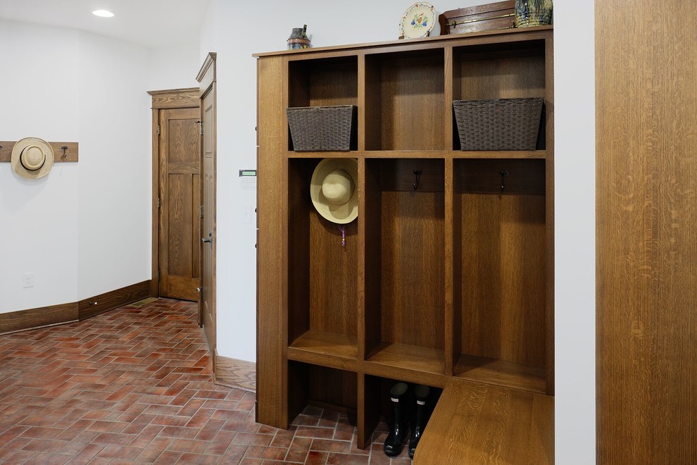 Example of a large arts and crafts brick floor mudroom design in Other with white walls