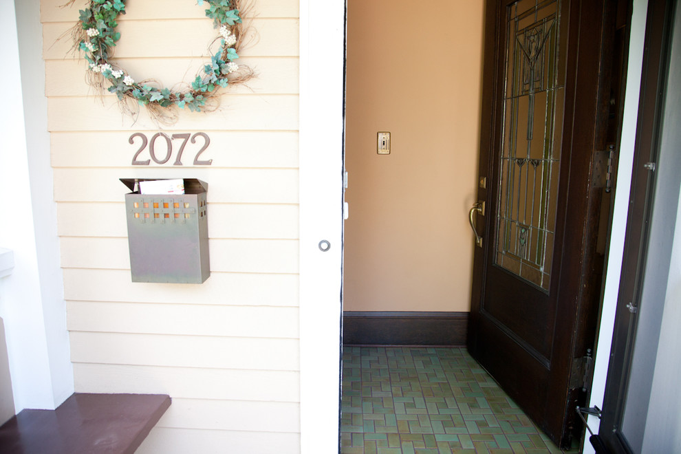 Imagen de puerta principal de estilo americano pequeña con suelo de baldosas de cerámica, puerta de madera oscura, paredes beige y puerta simple
