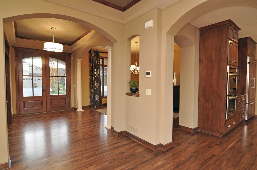 Idée de décoration pour une entrée craftsman avec un mur beige, un sol en bois brun, une porte double et une porte en bois brun.