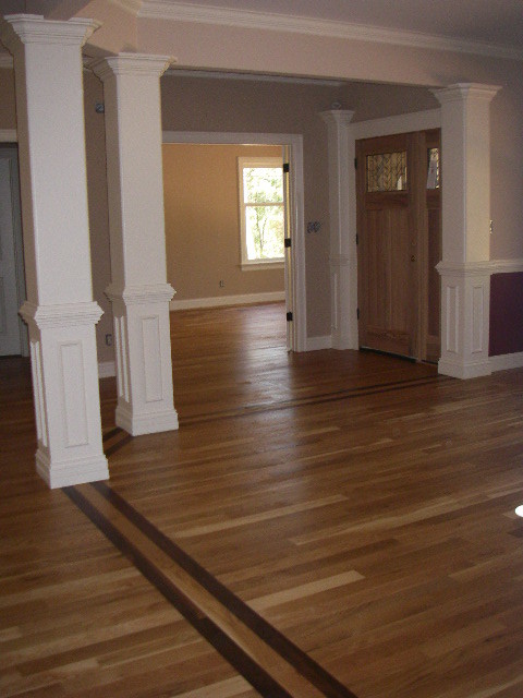 Cette image montre une entrée craftsman avec un mur beige, parquet clair, une porte simple et une porte en bois clair.
