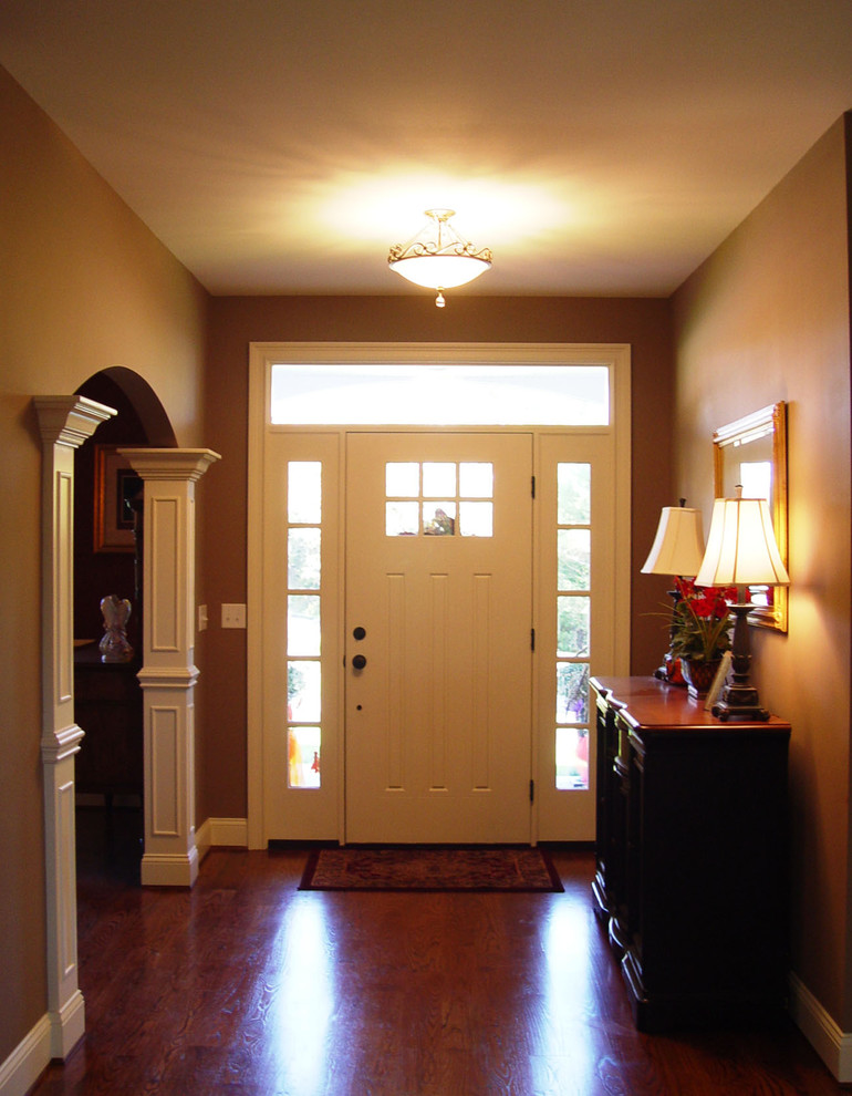 Bild på en mellanstor amerikansk foajé, med beige väggar, en enkeldörr, en vit dörr, mellanmörkt trägolv och brunt golv