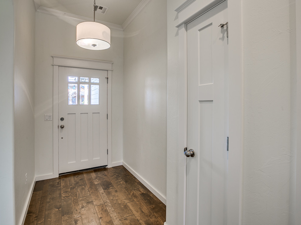 Ejemplo de puerta principal de estilo americano de tamaño medio con paredes grises, suelo de madera oscura, puerta simple, puerta blanca y suelo marrón