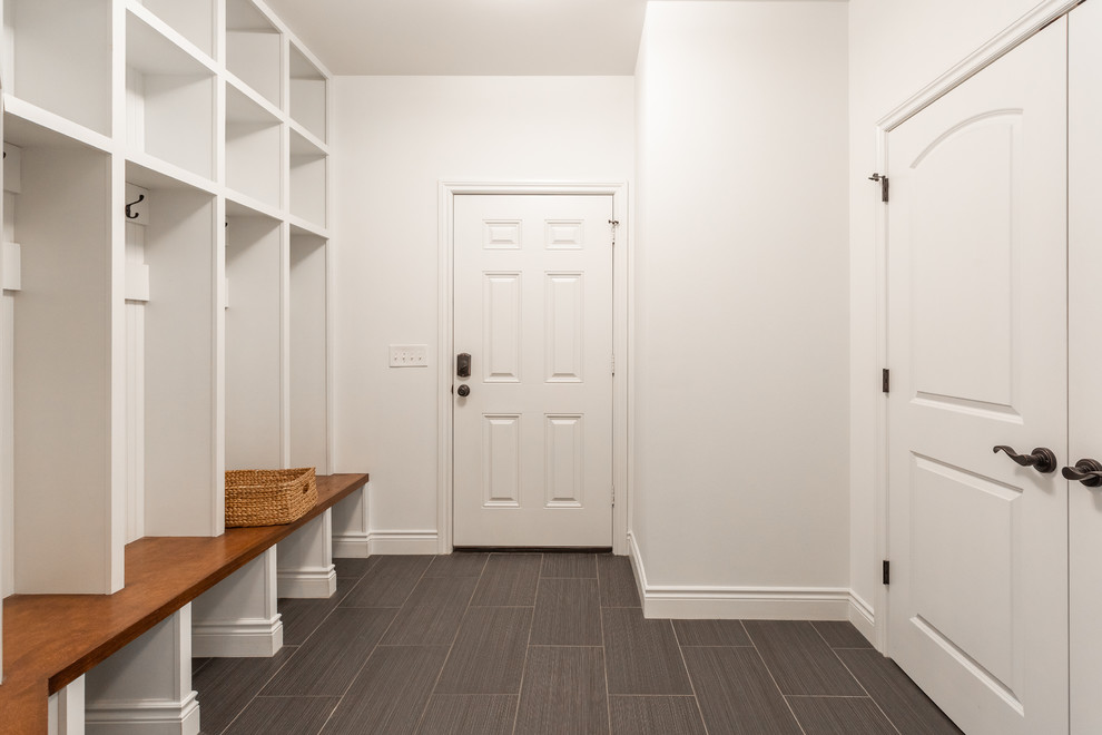 Exemple d'une entrée chic de taille moyenne avec un vestiaire, un mur blanc, un sol en carrelage de porcelaine, une porte simple, une porte blanche et un sol gris.