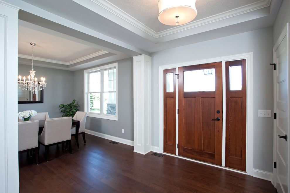 Klassisches Foyer mit grauer Wandfarbe, braunem Holzboden, Einzeltür und hellbrauner Holzhaustür in Minneapolis