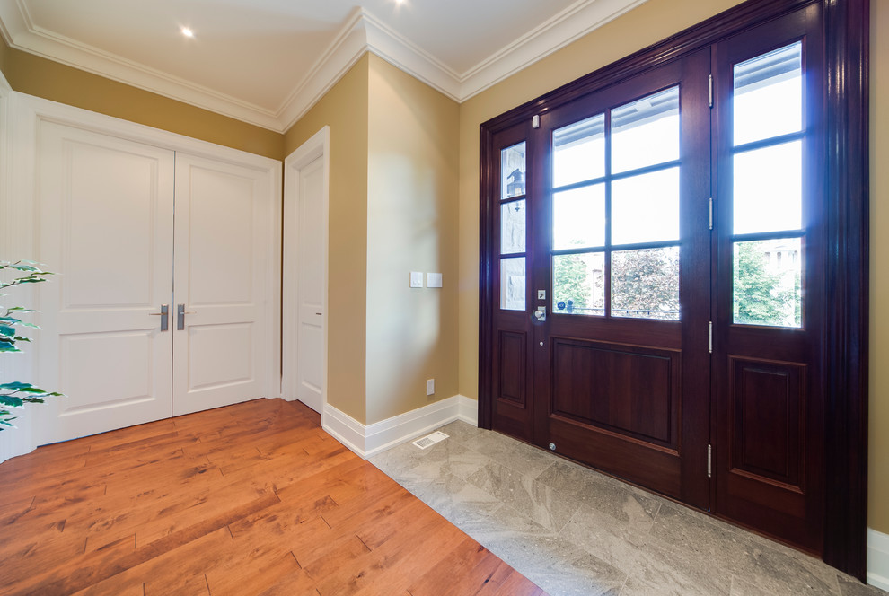Ispirazione per un grande ingresso con pareti gialle, pavimento in legno massello medio, una porta singola e una porta in legno scuro