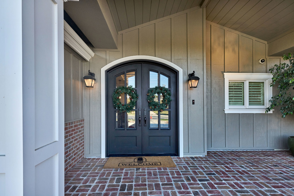 Idée de décoration pour une grande porte d'entrée craftsman avec un mur gris, un sol en brique, une porte double et une porte noire.
