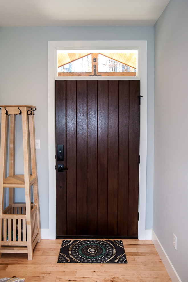 Cette photo montre une grande porte d'entrée craftsman avec un mur gris, parquet clair, une porte simple et une porte en bois foncé.