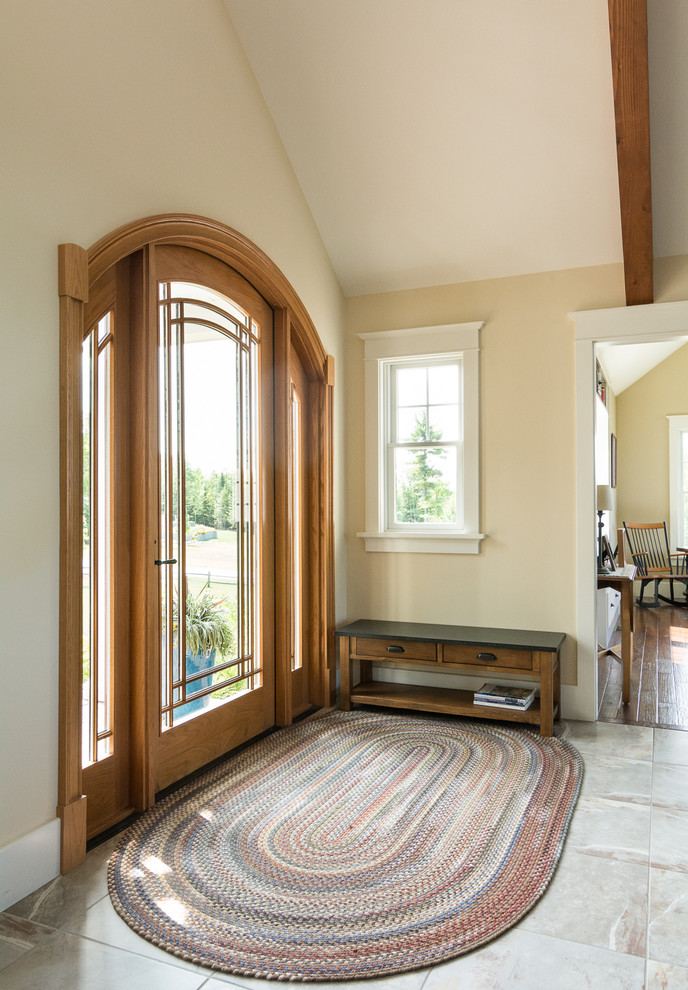 Cette photo montre une grande porte d'entrée craftsman avec un mur beige, une porte simple, une porte en bois brun, un sol en ardoise et un sol marron.