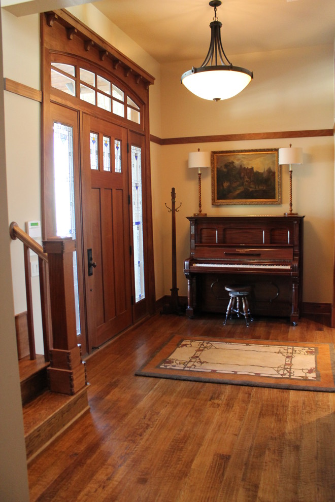 Ispirazione per un ingresso american style di medie dimensioni con pareti beige, pavimento in legno massello medio, una porta singola e una porta in legno bruno