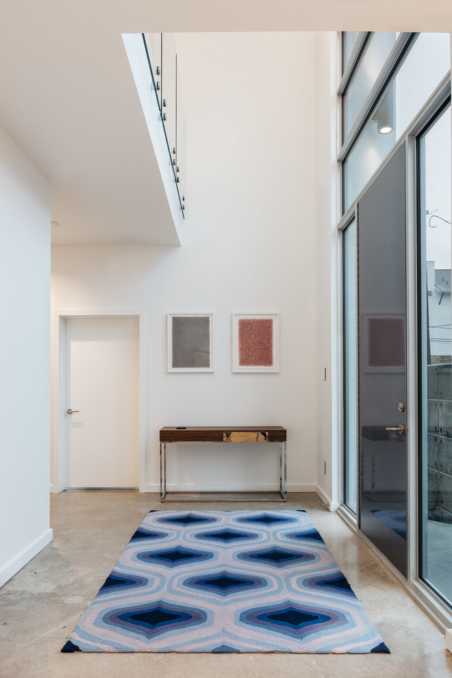 Ispirazione per un ingresso minimal con pareti bianche, pavimento in cemento, una porta singola e una porta blu