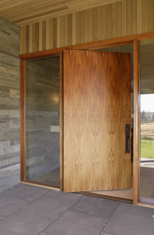 На фото: прихожая в современном стиле с поворотной входной дверью и входной дверью из дерева среднего тона